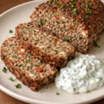 Mediterranean meatloaf served with garlic herb yogurt sauce on a plate
