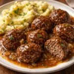 Salisbury steak meatballs served with creamy garlic herb mashed potatoes on a white plate